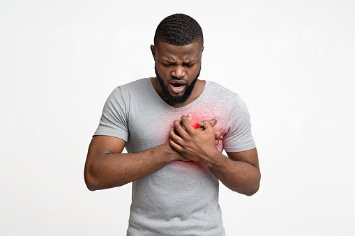 African guy having heart ache, holding hand on chest. Heart attack or stroke, white background
