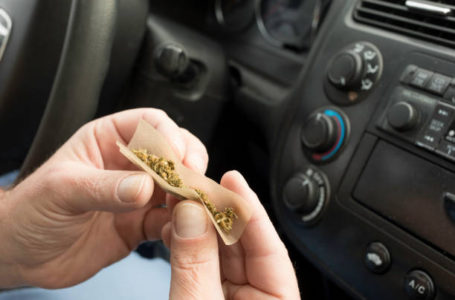 Stock photo of a man smoking marijuana in a vehicle driving a car under the influence of cannabis.
