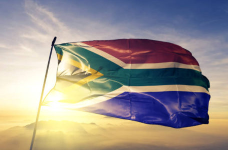 South Africa African flag on flagpole textile cloth fabric waving on the top sunrise mist fog