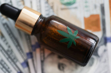Bottle of marijuana oil lies on banknotes. Share of drug trade in world economy concept