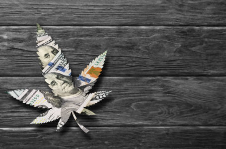 Marijuana, cannabis leaf made of dollars on wooden background