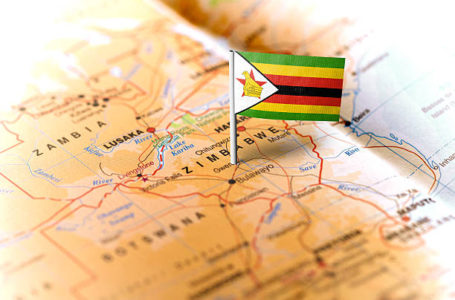 The flag of Zimbabwe pinned on the map. Horizontal orientation. Macro photography.