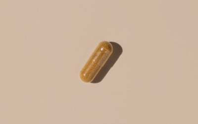 Brown medical capsule on light beige top view, hard shadows. Preventive medicine and healthcare, taking dietary supplements and vitamins.  Minimal composition