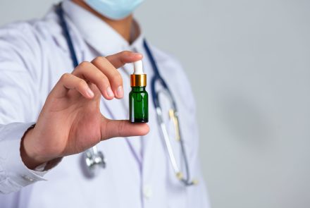 close-up-picture-of-medical-doctor-holding-a-bottle-of-cannabis-oil-on-white-wall-scaled-1.jpg