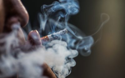 a closeup shot of a person puffing on a cigarette surrounded with smoke