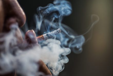a closeup shot of a person puffing on a cigarette surrounded with smoke