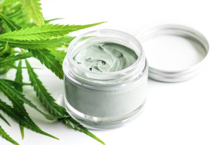 CBD cosmetics. Green cannabis plant and jar with a moisturizing rejuvenation cream.