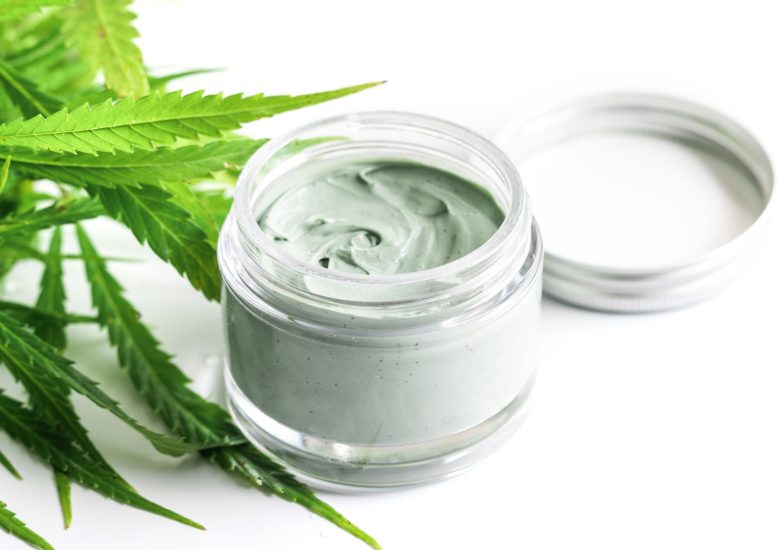 CBD cosmetics. Green cannabis plant and jar with a moisturizing rejuvenation cream.