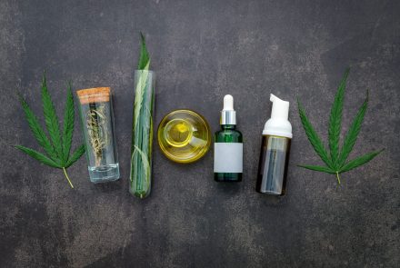 Glass bottle of cannabis oil and hemp leaves set up  on concrete background.